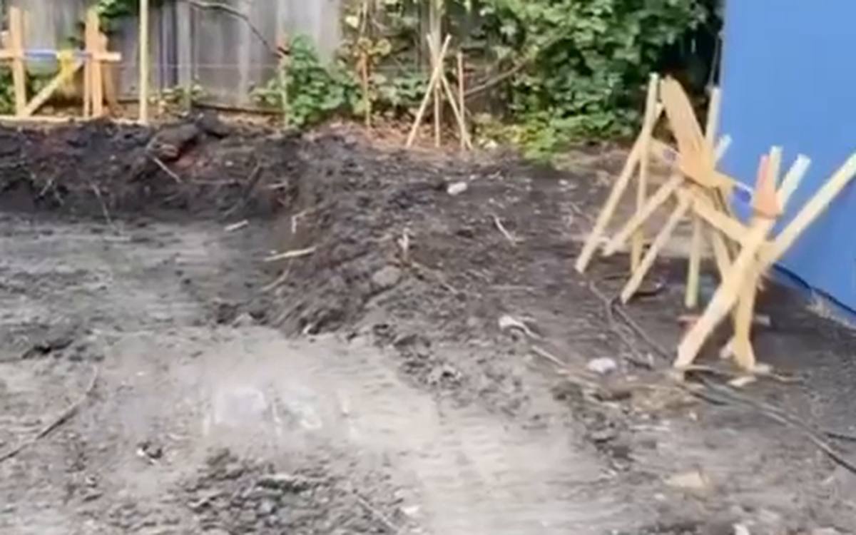 Back yard cut to grade with layout stakes along the fence line