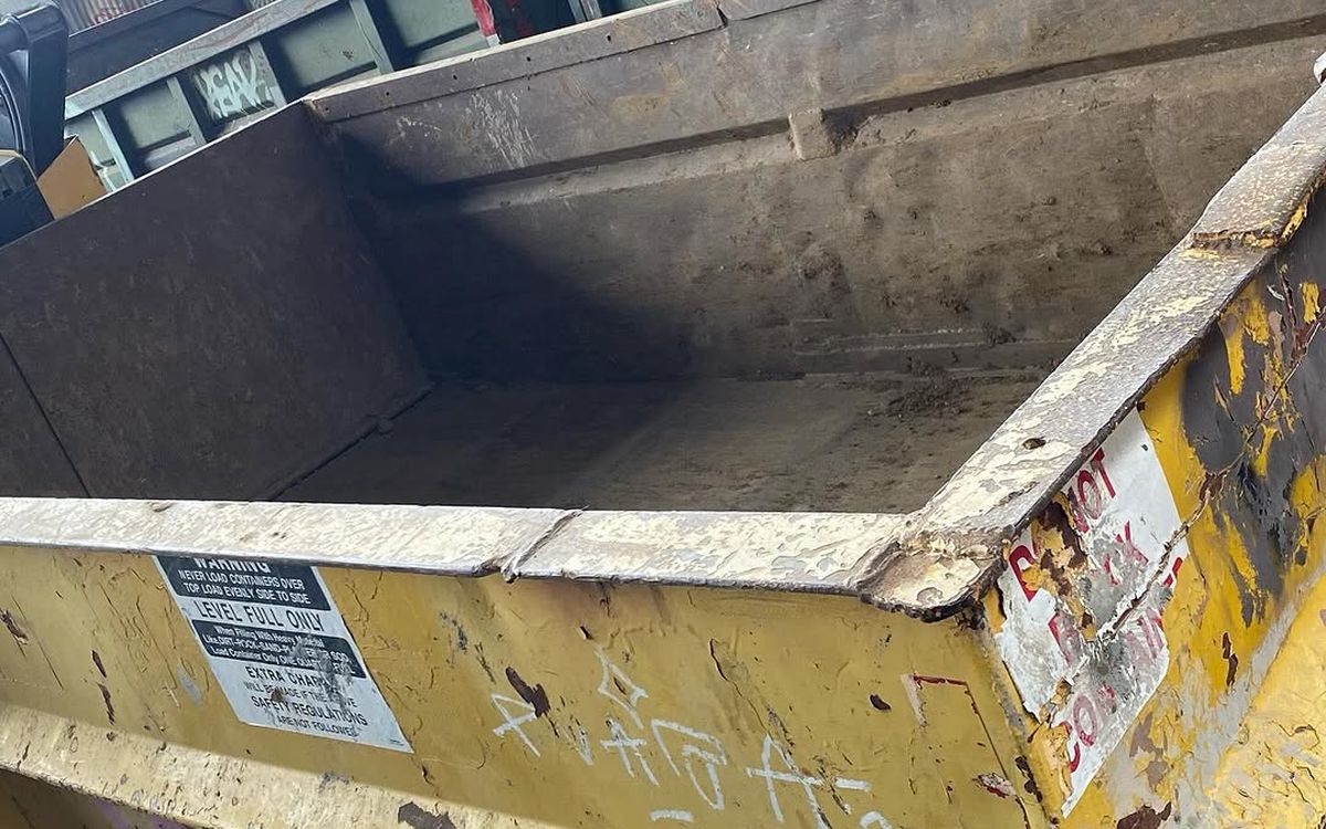 Roll-off containers stacked at the yard with the level-full warning label visible