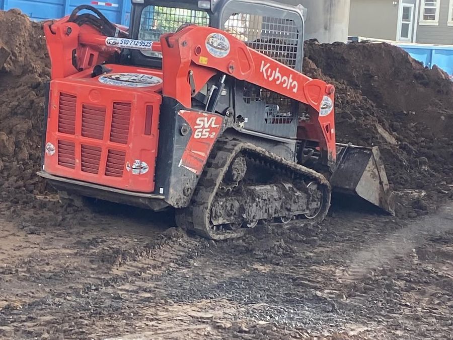 Tracked loader working soil on an open cut with the spoil banked back