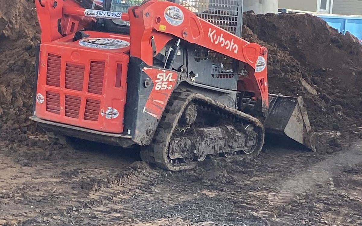 Tracked skid loader moving soil on an open excavation