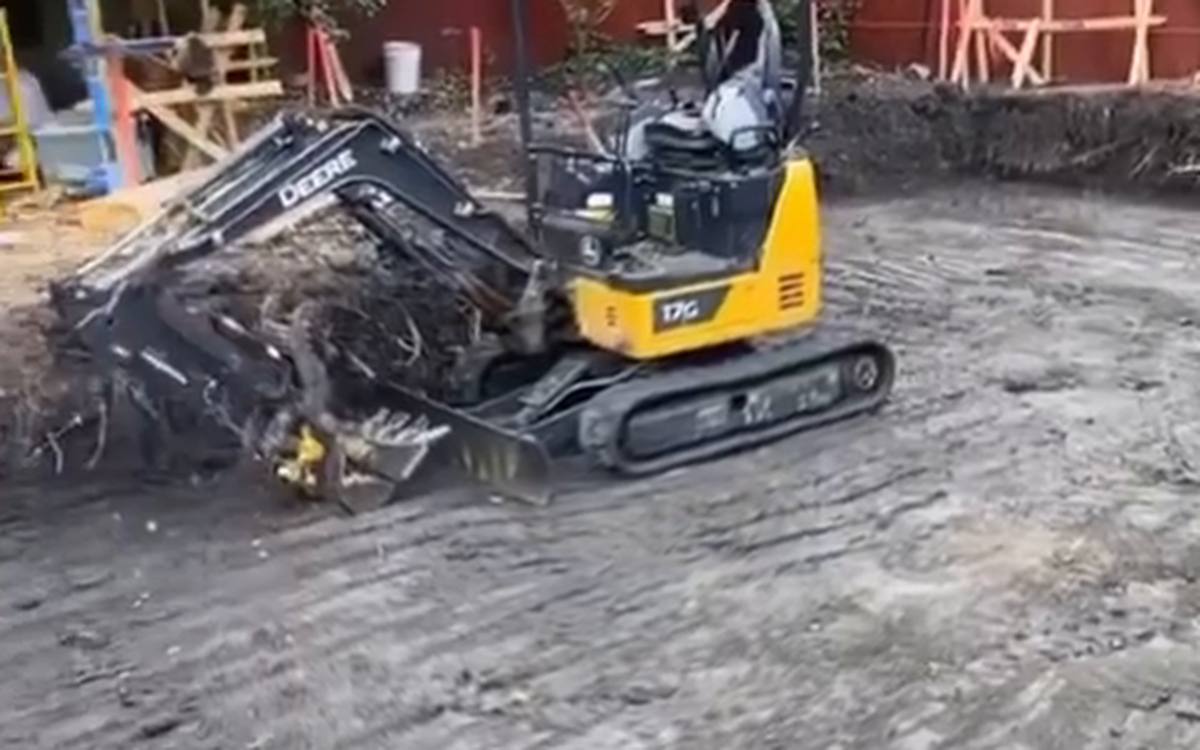 Compact excavator opening a cut on a fenced back yard site