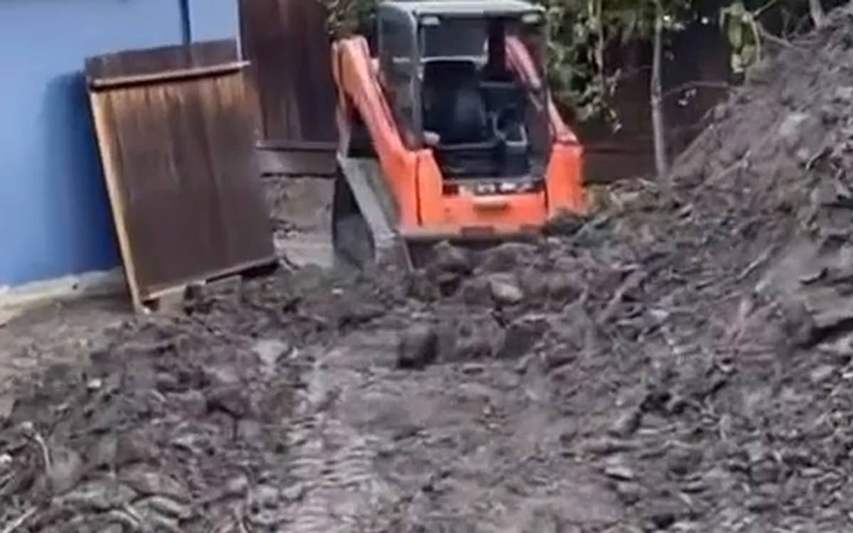 Tracked loader cutting into a soil bank, exposing the layers below the surface