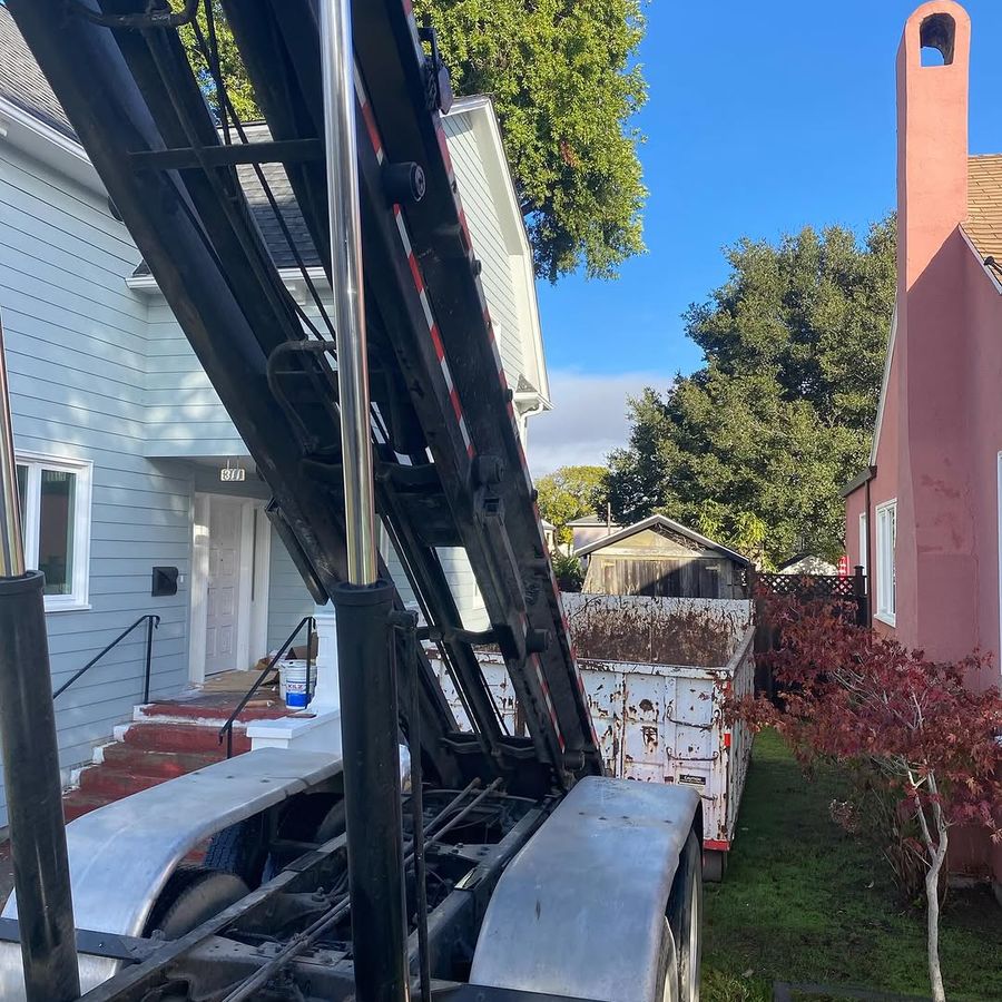 Container being lowered down a narrow side yard by a raised hoist