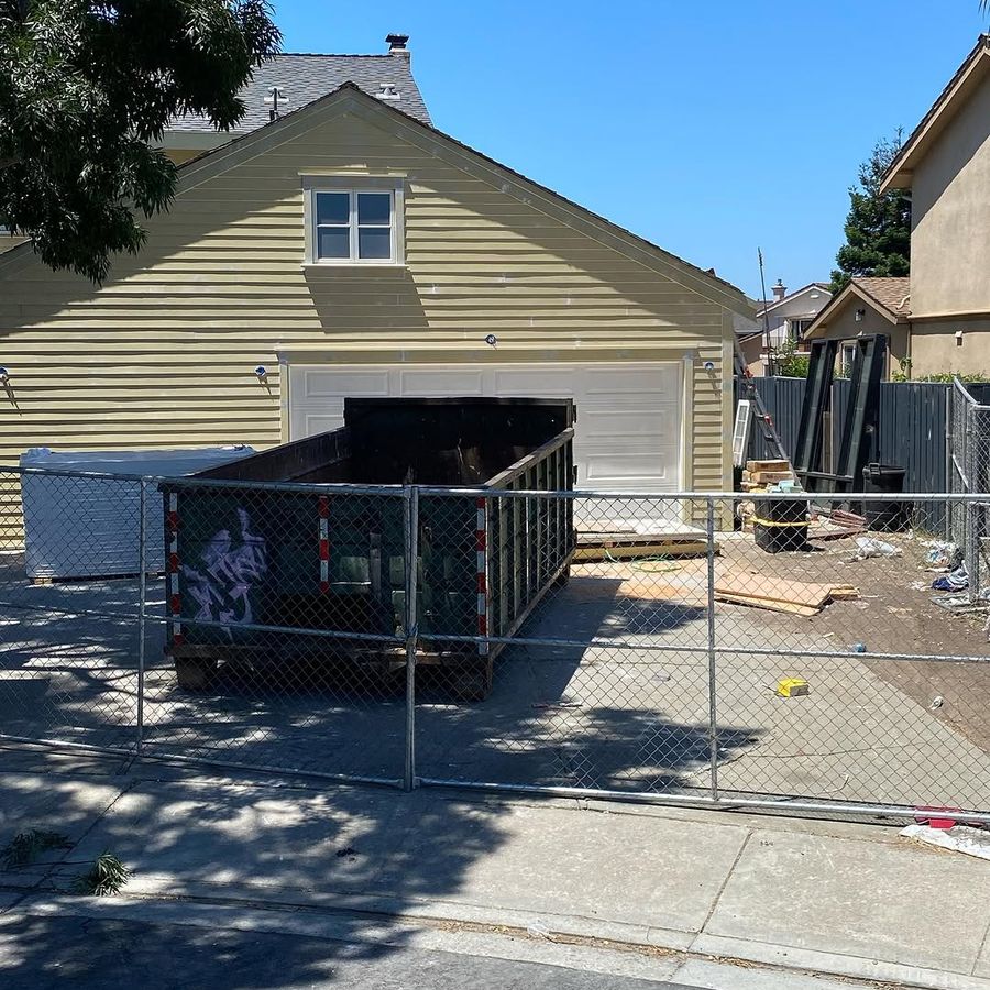 Roll-off container inside a temporary fence at a job site