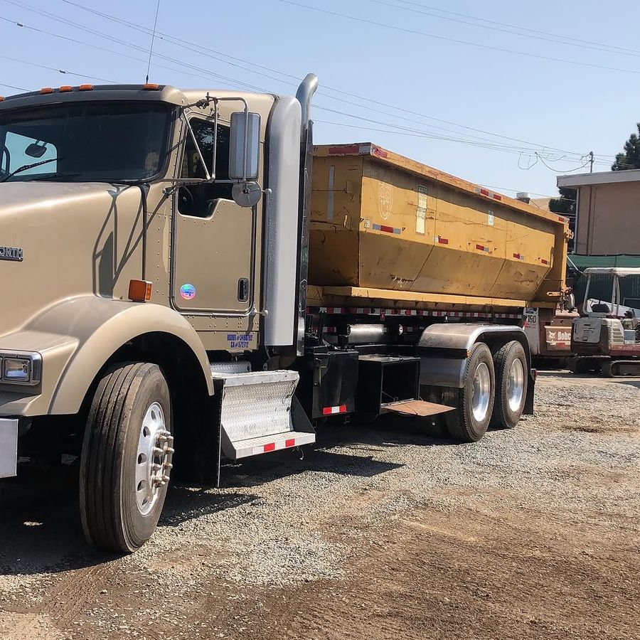 Loaded dump truck alongside a tracked excavator at the yard