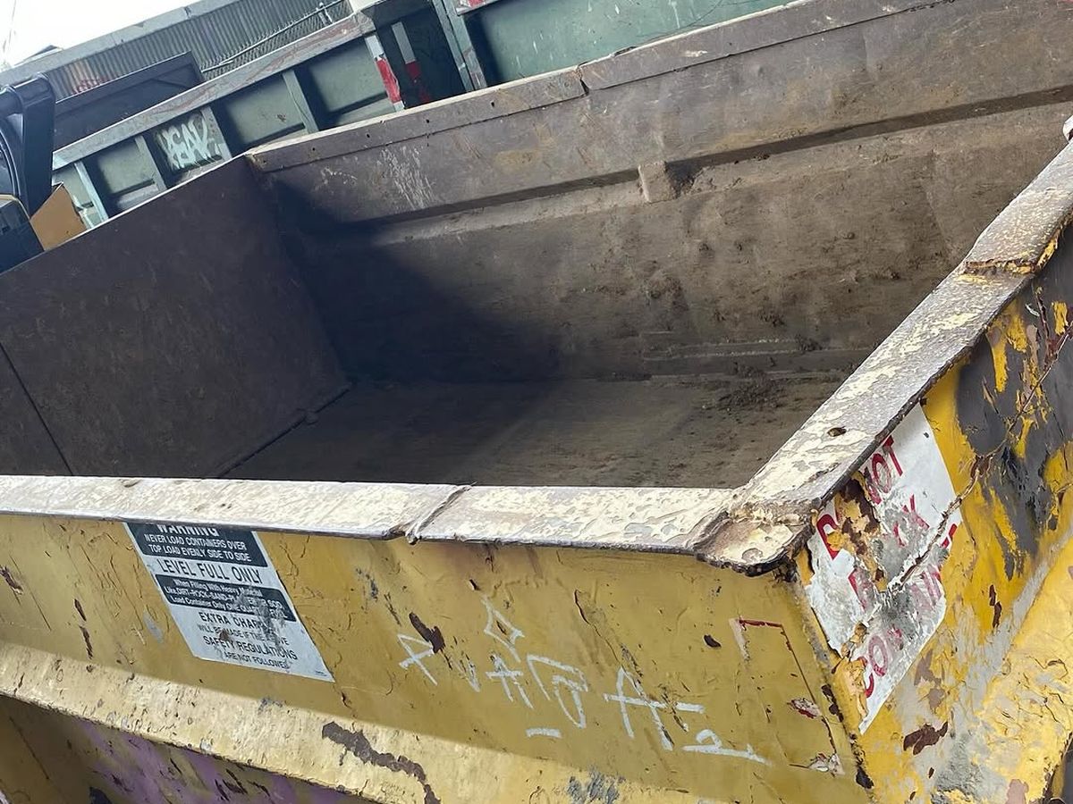 Empty roll-off containers stacked at the yard, one showing the level-full warning label