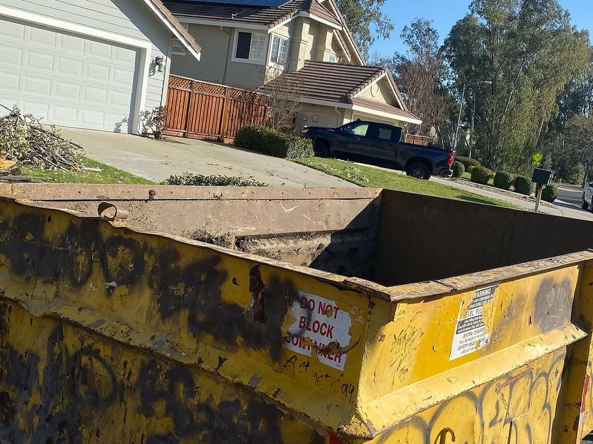 Yellow roll-off container set on a residential driveway