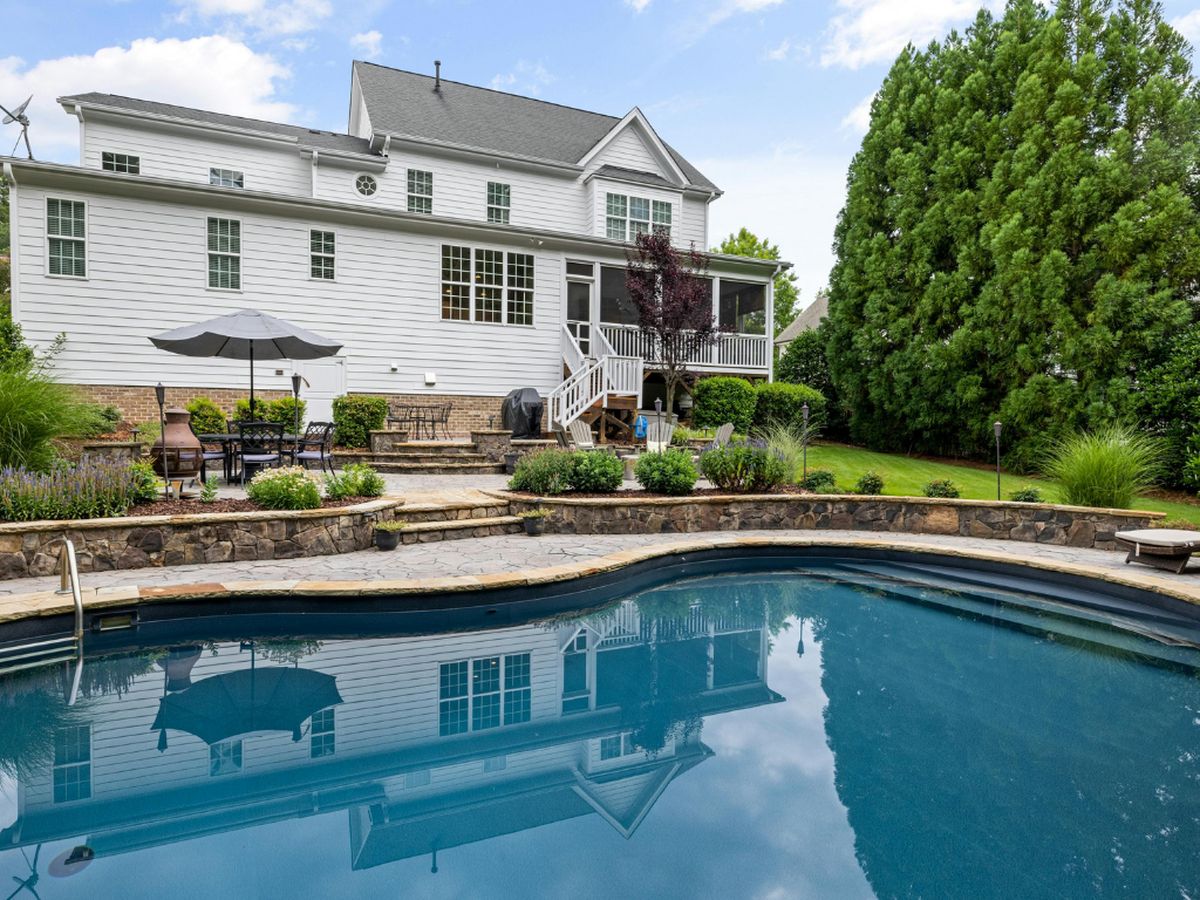 An in-ground pool in a suburban back yard with the house behind it, the starting point for a removal