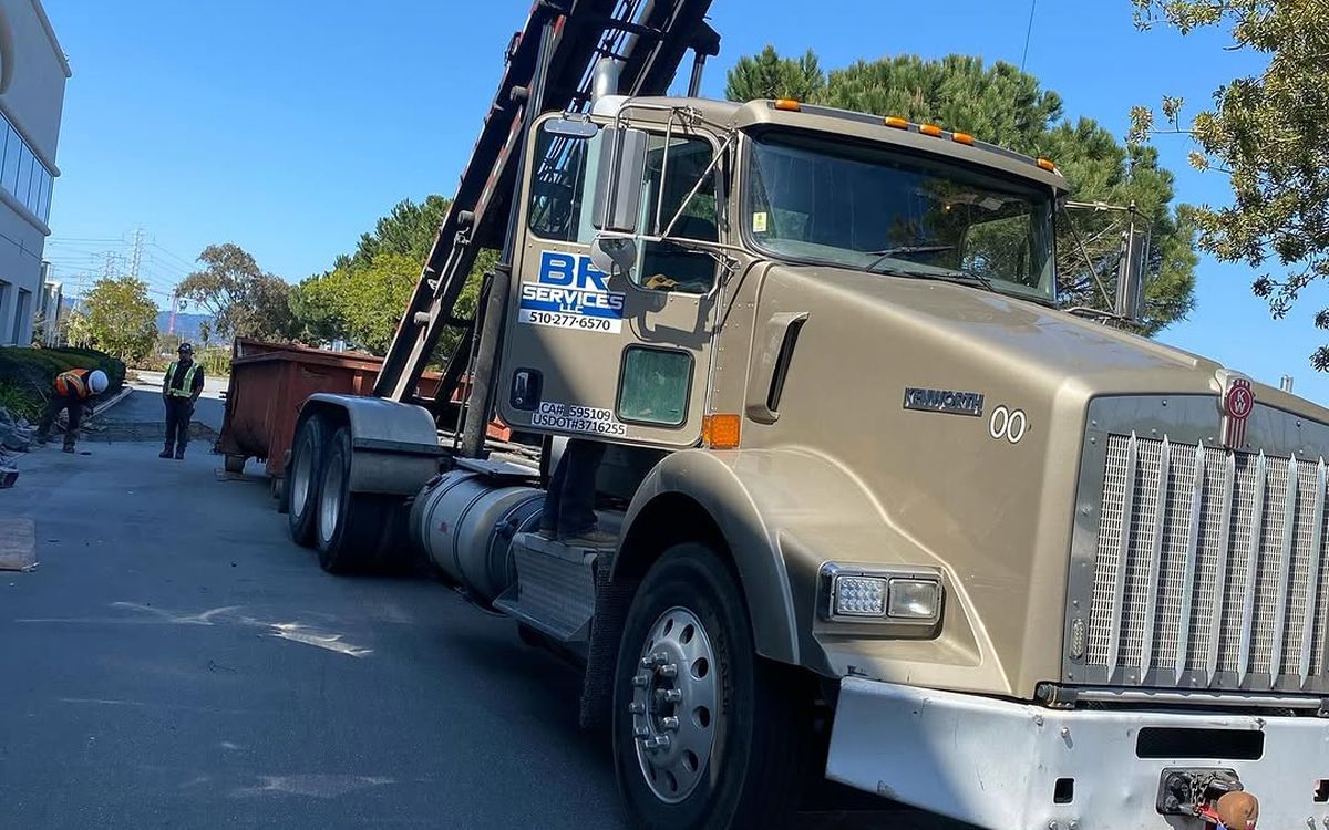BR Services roll-off truck on a street with a container loaded behind the cab