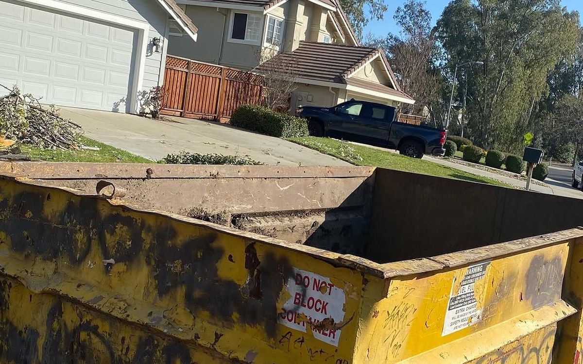 Yellow roll-off container set on a residential driveway with the approach kept clear